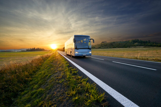 En buss som kör på en väg i solnedgång